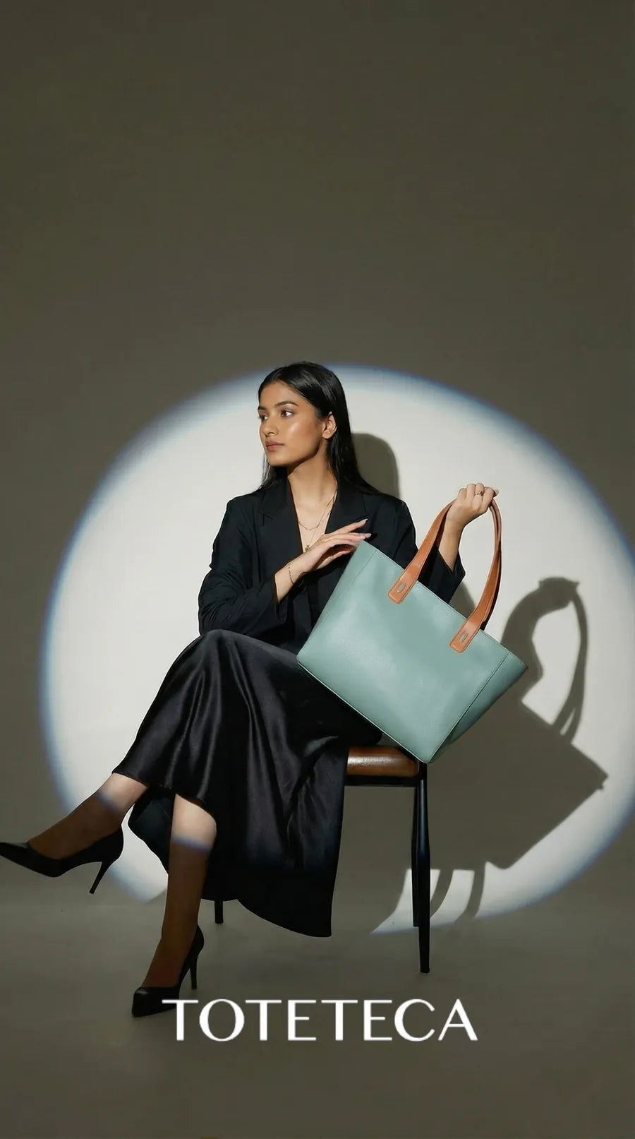 Toteteca campaign - model seated in a spotlight with a mint tote