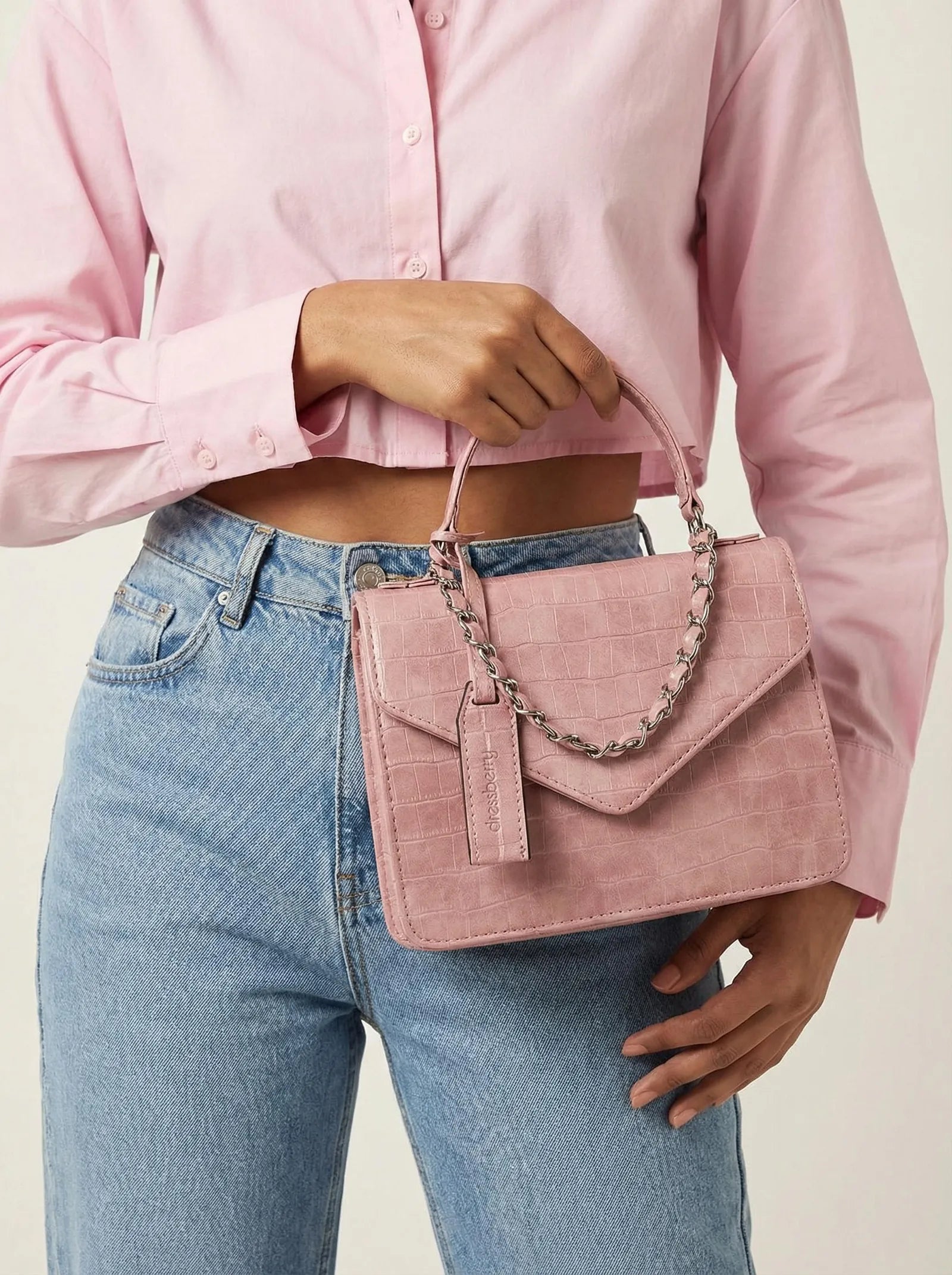 Blush pink croc Toteteca bag with silver chain, carried with a pink shirt