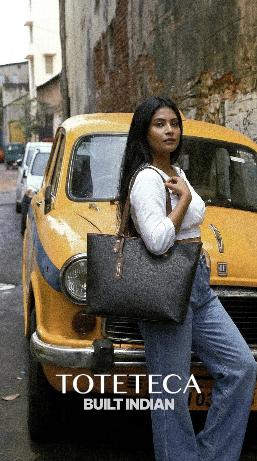 Toteteca campaign - model with a black tote beside a vintage yellow taxi