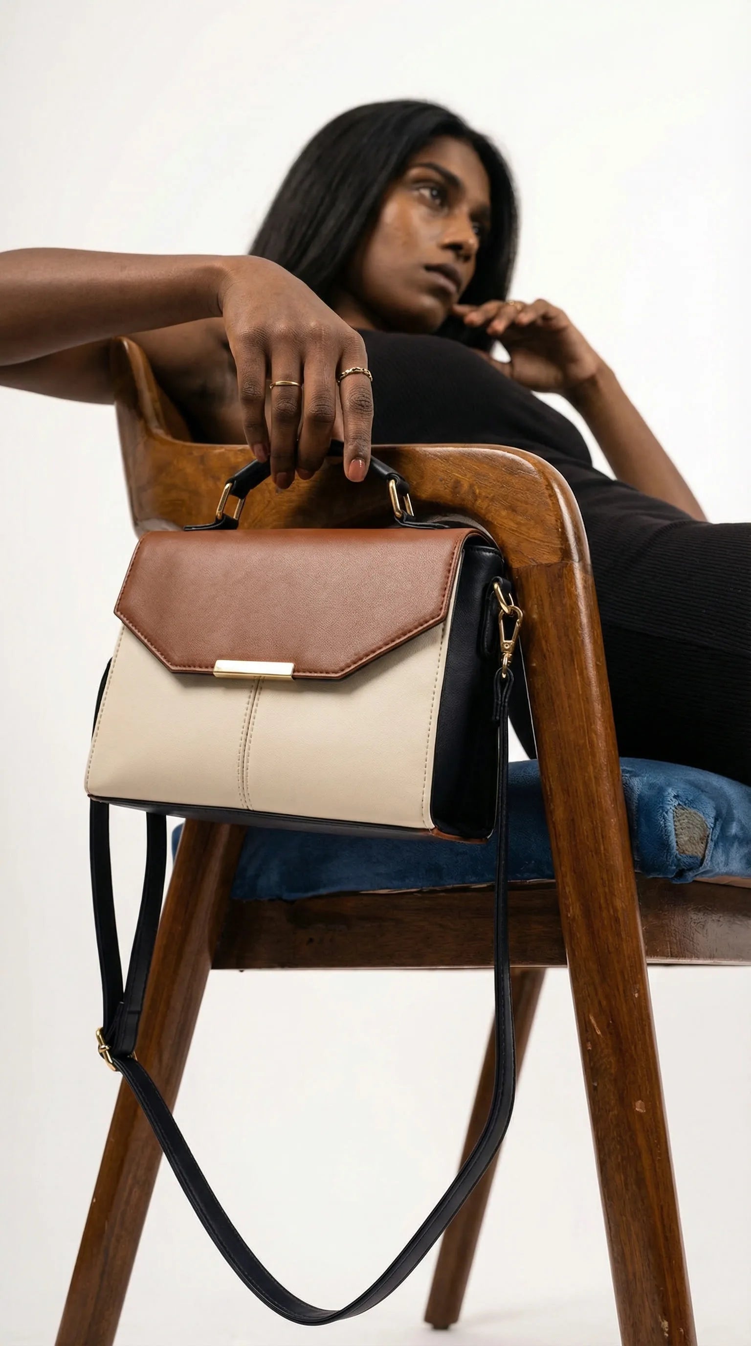 Toteteca colour-block top-handle bag in tan, cream and black resting on a wooden chair