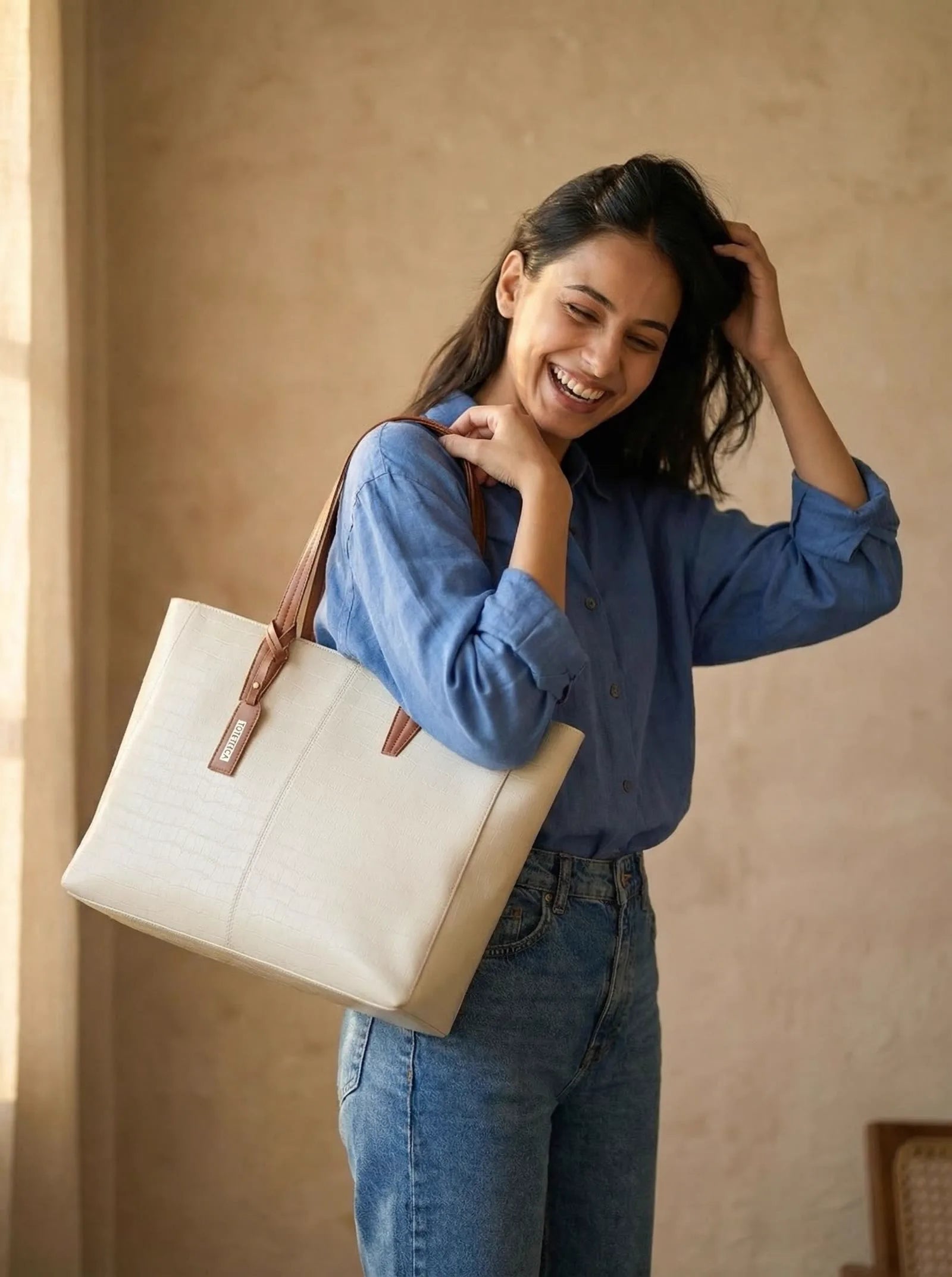 Laughing woman in a blue shirt with a cream croc-texture Toteteca tote on her shoulder