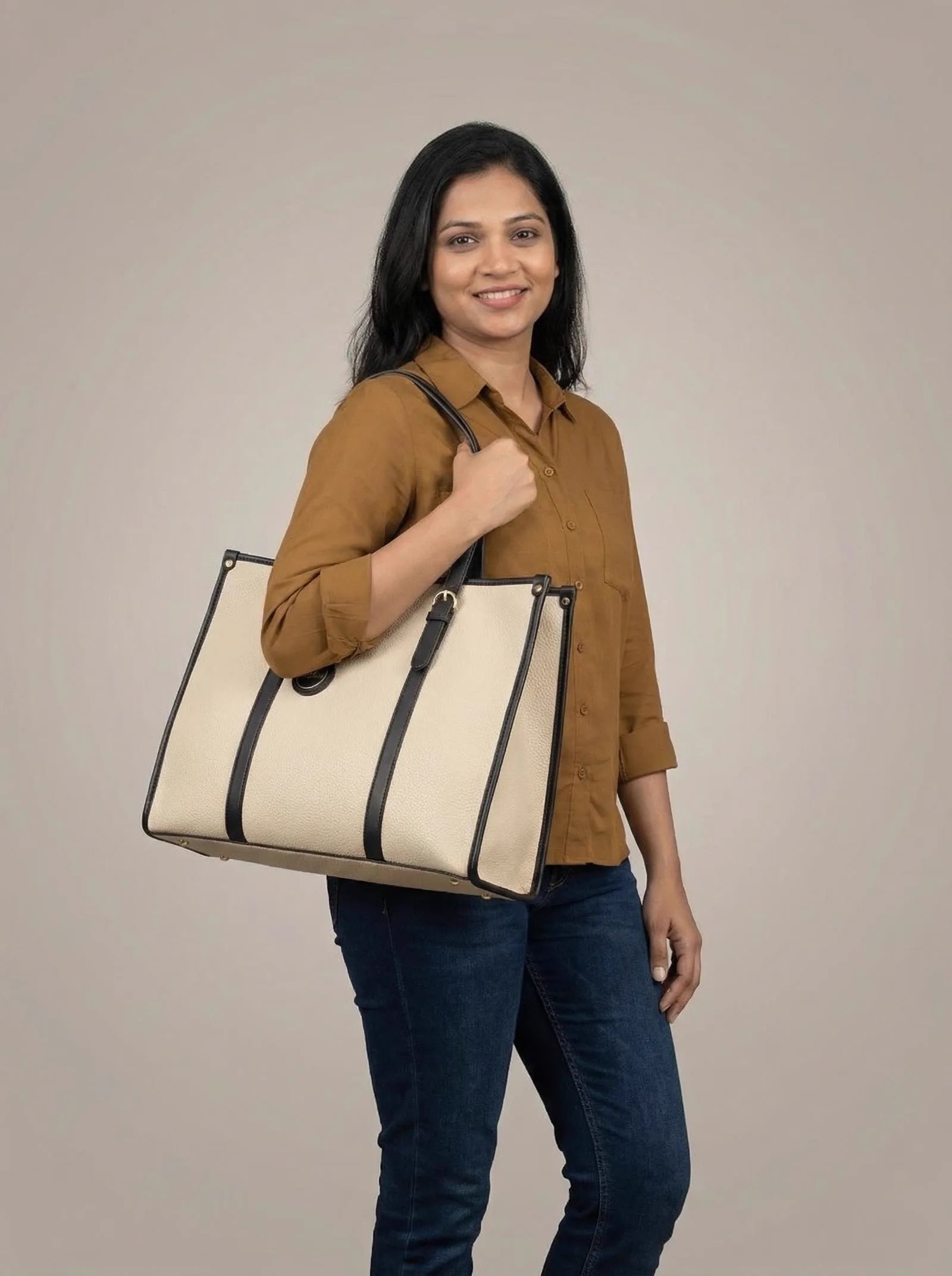 Smiling model in a tan shirt with a cream Toteteca tote with black straps