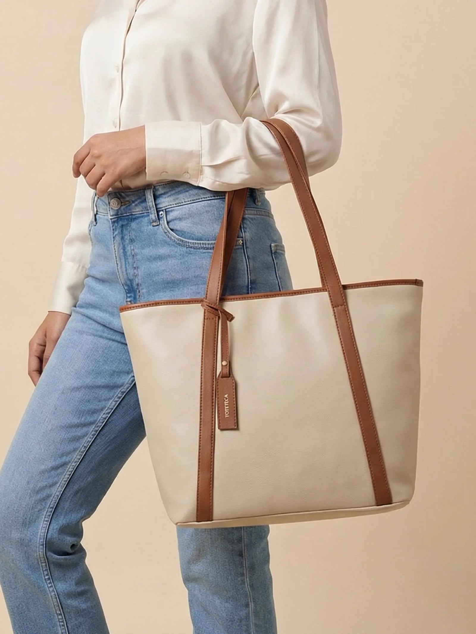 Cream Toteteca tote with tan straps carried with light-wash jeans