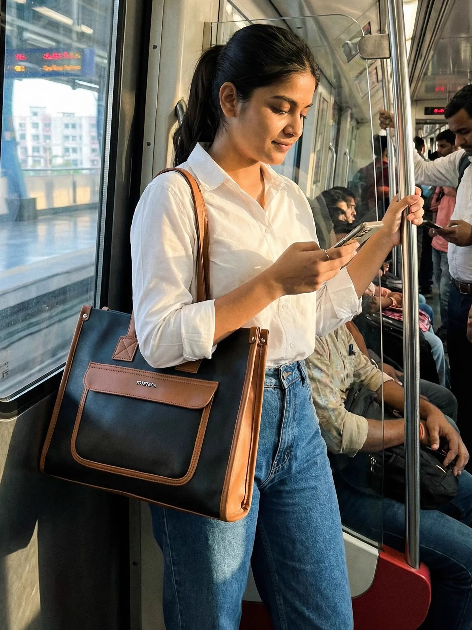 Young woman on the metro carrying a black and tan Toteteca office tote