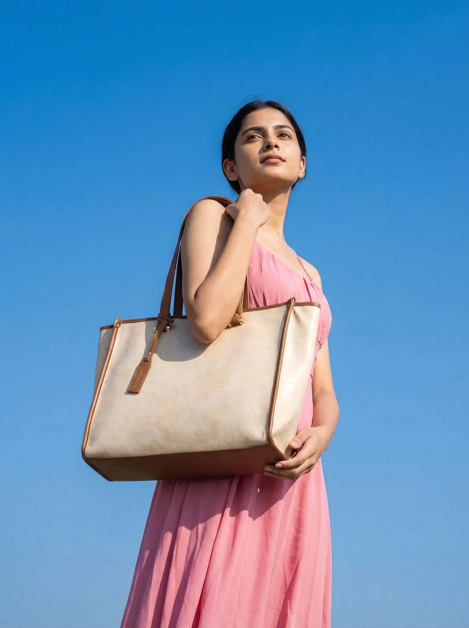 Model in pink against a blue sky with an off-white Toteteca tote