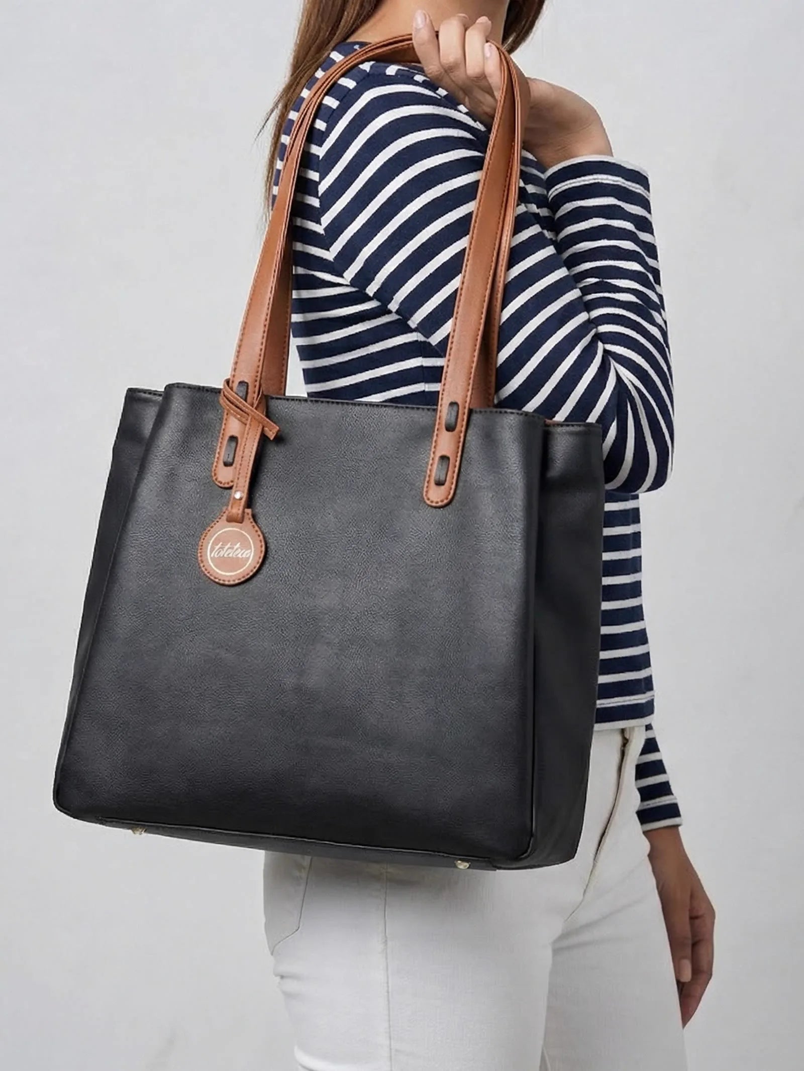 Woman in a striped top carrying a black Toteteca tote with tan handles