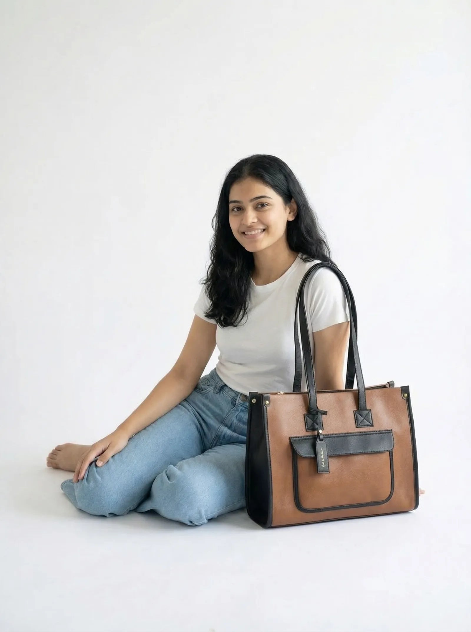 Model seated on the floor with a tan Toteteca tote with black pocket and straps