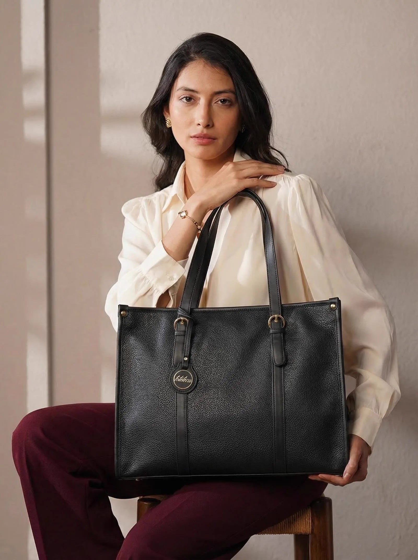Model seated with a structured black Toteteca work tote — an example of Toteteca's manufacturing quality